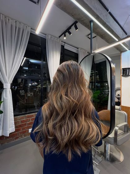 A beautiful brunette balayage with soft, flowing waves that showcase the seamless blend of colors.