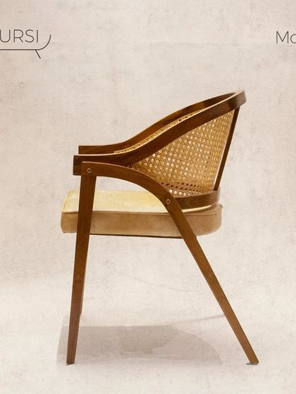 The 'Modis' dining chair, designed for comfort during long meals. It features a cushioned seat and a curved, angled backrest made of teak and rattan.