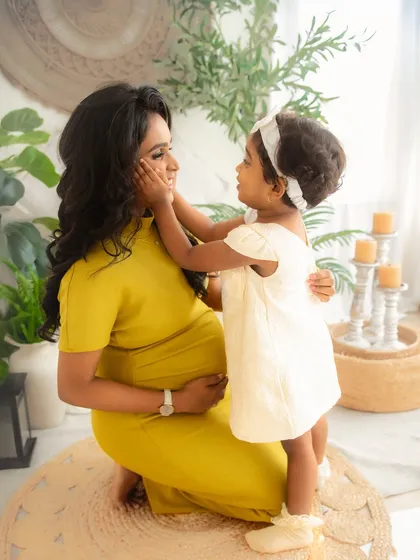 Welcoming a new baby is a journey for the whole family. Here, a mother-to-be shares a tender moment with her daughter, beautifully capturing the love and anticipation before the new arrival during a maternity photoshoot.
