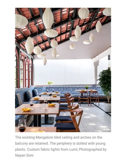 This Elle Decor feature highlights the blend of old and new on the balcony. The retained Mangalore tiled ceiling is complemented by custom fabric lights from Lumi, creating a unique and inviting atmosphere.