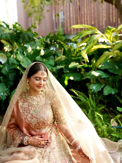 A serene moment captured in a garden setting. The natural light enhances her soft glam makeup, making her look like she's glowing from within.