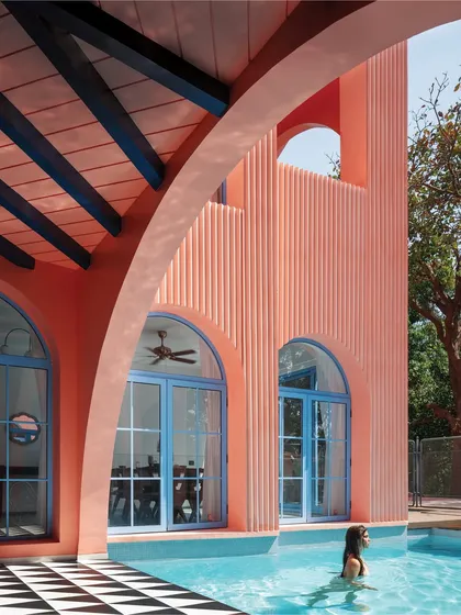 The poolside at Baia Villas is a study in contrasts. The vibrant peach facade and blue window frames are balanced by the classic black-and-white checkered flooring, creating a space that feels both energetic and timeless.