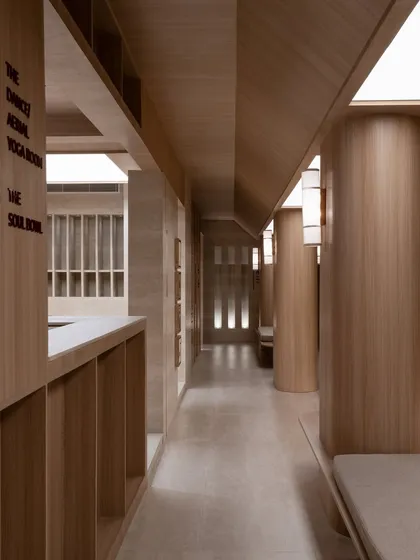 A view down the main corridor, showing the axial alignment and the seamless transition between spaces. The signage is integrated directly into the wood paneling.