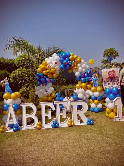 A wide shot of the complete outdoor setup, including the large 'ABEER' letters, balloon arch, and themed props.