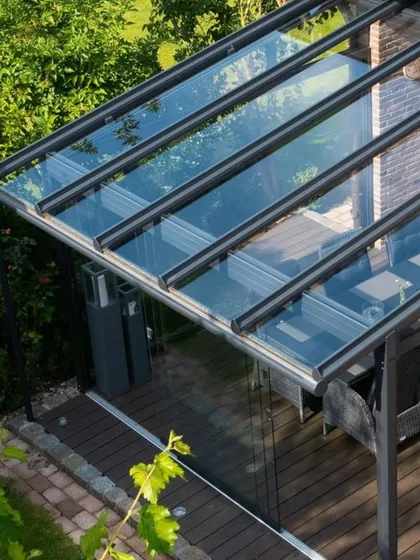 An aerial view of a glass enclosure we built for a patio. The structure is designed to fit the exact dimensions of the space, creating a seamless, fully-enclosed sunroom with clear views of the surrounding garden.