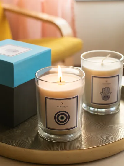 Our Evil Eye and Hamsa candles, designed to bring positive energy into your space. The Evil Eye candle features an Apple Cinnamon fragrance, while the Hamsa candle offers the comforting scent of Vanilla Grace.