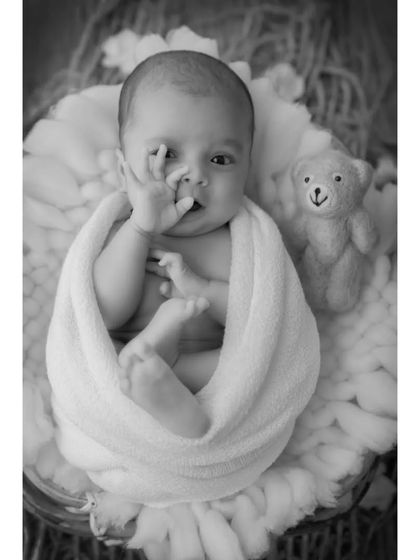 This black and white portrait captures a fleeting, thoughtful expression. The focus is entirely on the baby's face and gesture, creating a simple yet powerful image.