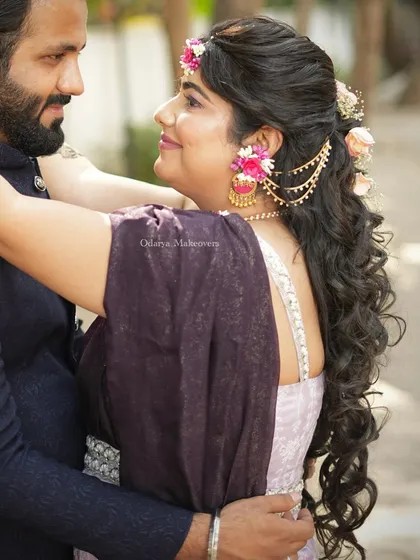 A romantic couple shot during the Mehendi ceremony. The bride's hairstyle is a beautiful cascade of curls adorned with floral accessories.