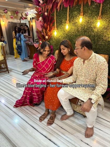 A candid moment showing the bride with her parents. Her beautiful lotus foot mehendi is visible, adding a touch of grace and tradition to this heartfelt scene.