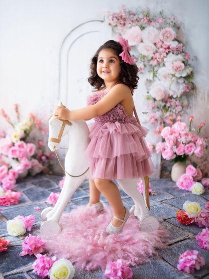 A classic rocking horse photo, set against a beautiful backdrop of pink and white flowers.