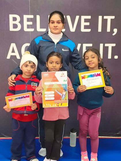 A coach poses with three of her students, all proudly holding their new certificates.