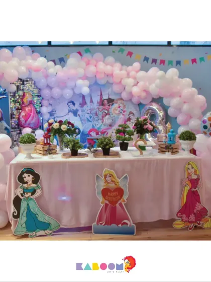 A dreamy Disney Princess party with a soft pink balloon arch and a backdrop featuring all the iconic princesses, creating a royal celebration for the birthday girl.