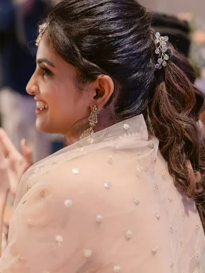 A side profile showcasing the intricate hairstyle with a delicate hair accessory. The makeup is kept soft and romantic to complement the overall look.