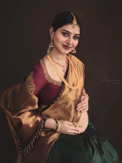 A classic seated portrait that radiates elegance and grace. The rich colors of the saree and the warm, moody lighting come together to create a photograph that feels like a classic painting.