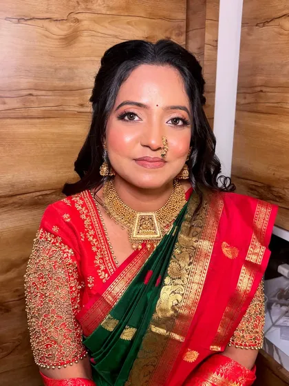 A classic portrait of the bride looking directly at the camera. Her soft glam makeup, with defined eyes and a neutral lip, complements her vibrant green and red saree beautifully.