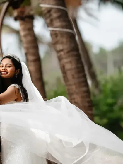 A playful moment from a Goa beach shoot. The bride's veil is caught in the wind as she leans back, creating a beautiful, dynamic image full of life and movement.