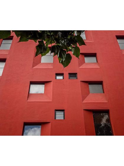 The play of reflections and shadows on the deeply recessed windows adds complexity and life to the building's monolithic facade.