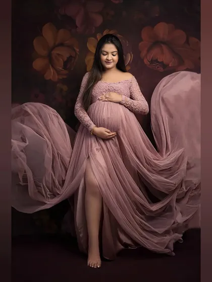 Lost in a dream. This full-length portrait captures the elegance of our dusty rose gown, with its delicate lace and flowing tulle creating a soft, romantic feel against a floral backdrop.