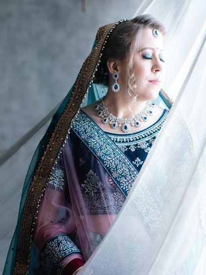 A serene portrait of the bride by a window, the soft curtain adding a delicate, dreamy quality to the image.