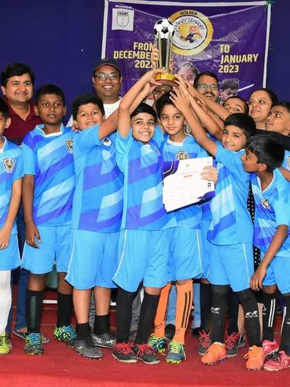 The Under 10 team with their runners-up trophy from the Baby League, surrounded by proud parents and coaches. Our academy is a community effort.