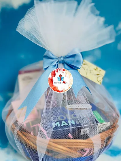 A classic wicker basket hamper designed for him, beautifully wrapped in white and blue tulle with a satin bow. These baskets can be customized with a variety of products, from grooming essentials to gourmet snacks.