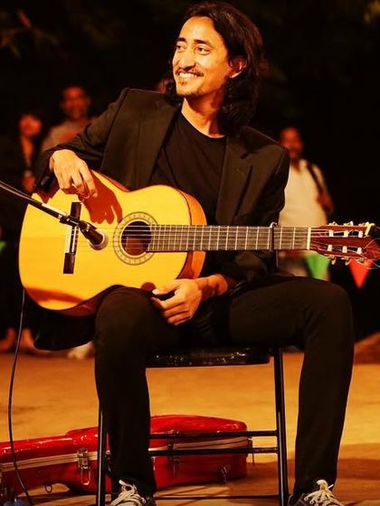 My talented flamenco guitarist smiling at the audience during an outdoor festival performance.