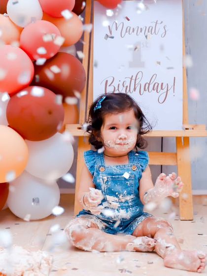 Confetti, cake, and a happy baby. This photo captures the fun and festive atmosphere of a first birthday cake smash session.