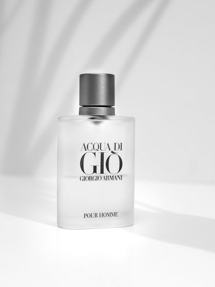 A high-key, black and white style photograph of Acqua Di Gio perfume. The soft shadows and clean background create a timeless and elegant look.