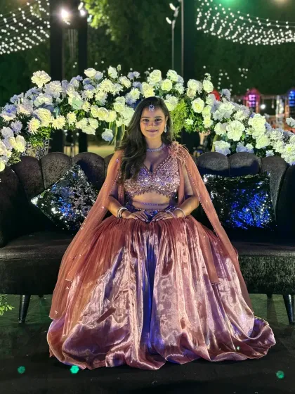 Seated on a plush couch amidst the beautiful floral decor of the Sangeet venue.
