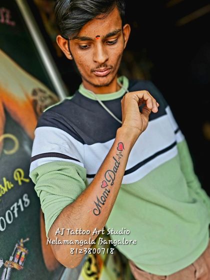 A "Mom Dad" tattoo on the forearm, complete with a heartbeat line and a heart.