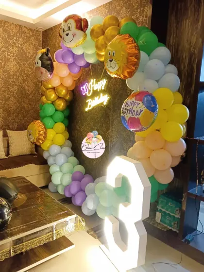 A home-based jungle theme birthday party with a balloon ring, animal foils, and a light-up number '8'.
