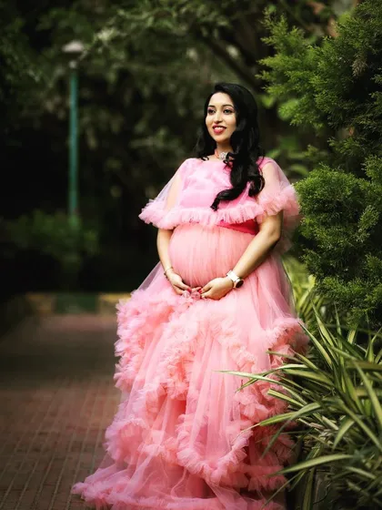 The off-shoulder capelet and cascading ruffles of this pink maternity gown add a touch of whimsy. It’s perfect for outdoor photoshoots in parks and gardens.