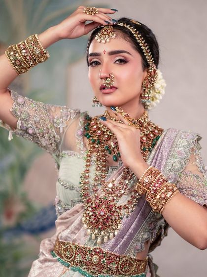 A powerful pose that highlights the bride's confidence and the stunning details of her attire, from the layered necklaces to the bangles.