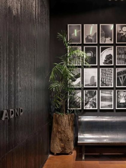 The entrance lobby of the ADND office, where a polished steel bench and a gallery wall create a space that feels both industrial and curated.