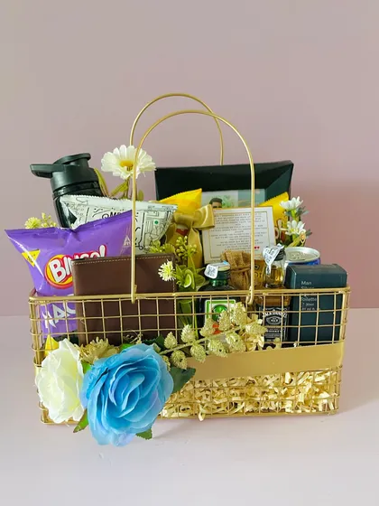 A metal hamper basket curated for Rakhi. It's filled with gifts for a brother, including a wallet, snacks, and grooming items.