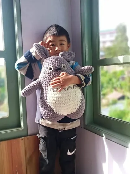 Seeing the joy my creations bring is the best reward. Here is a happy customer with a large, cuddly Totoro plushie I made, perfect for fans of Studio Ghibli.