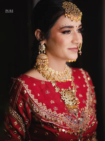 A classic bridal portrait focusing on the intricate details of the bride's jewelry, from her oversized jhumkas to her stunning necklace.