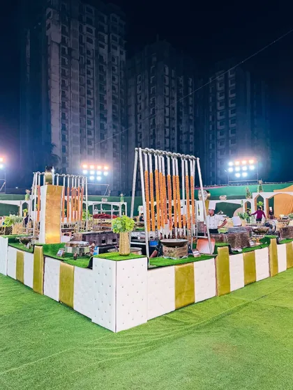 A stunning, modern catering setup with white and olive-green counters, featuring unique hanging kebab displays.