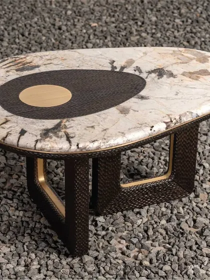 This unique table features a Patagonia marble top with a distinctive chiseled wood and brass inlay. The base is crafted from woven rattan, creating a beautiful contrast of textures and materials.