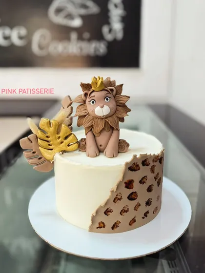 A modern and stylish lion cake. The design features a handcrafted fondant lion king and a leopard print pattern on the side for a chic jungle theme.