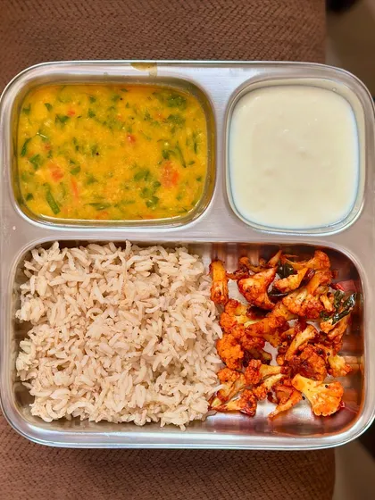 A simple lunch of brown rice, dal, sautéed cauliflower, and curd. This is a staple meal that is both healthy and easy to prepare.