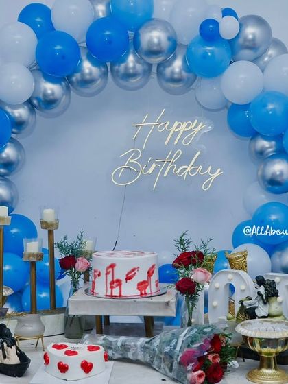 The same setup without the smoke effect, showcasing a beautiful blue and silver balloon arch with elegant candle stands and floral arrangements.