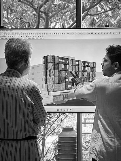 A conceptual design discussion in the studio. We review a 3D model on screen, pointing out details and debating the direction of a new facade design.
