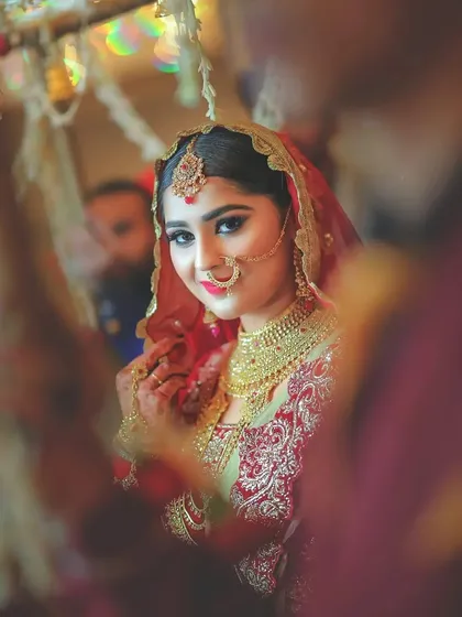 A lovely shot of the bride looking into a mirror, capturing her reflection and her beautiful smile on the wedding day.