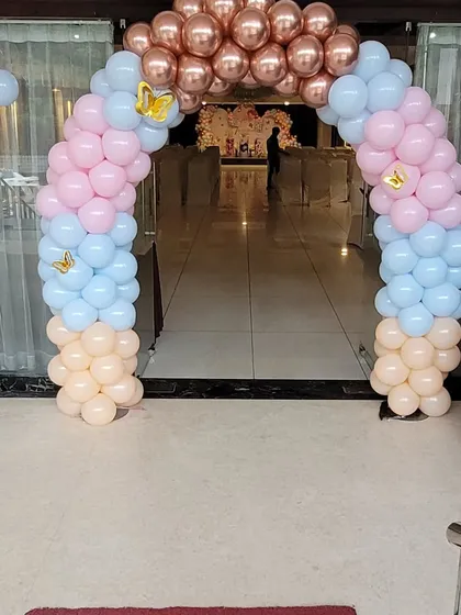 A beautiful balloon arch in pastel pink, blue, and peach with gold butterfly accents, creating an inviting entrance for the butterfly-themed party.