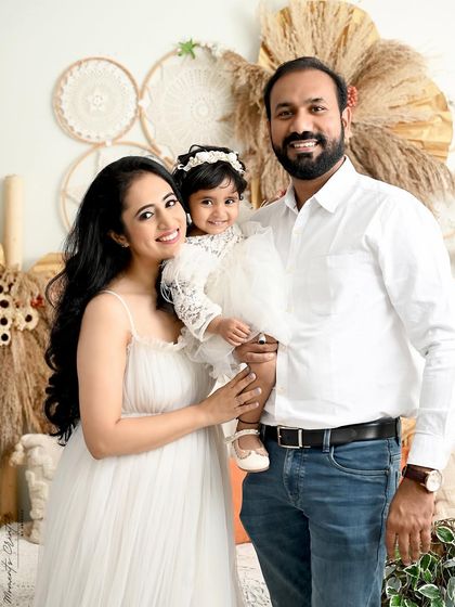 A classic family portrait with a bright, bohemian feel. The family's coordinated white outfits look beautiful against the natural textures of the backdrop.