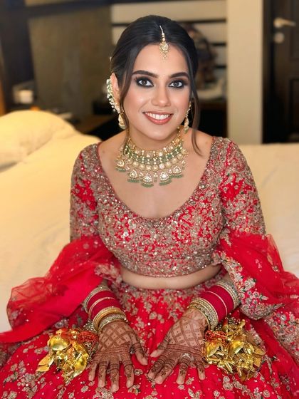 A close-up of the bride's happy face, with her elegant updo visible. The hairstyle is designed to complement her maang tikka and other bridal jewelry perfectly.