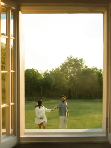 A beautiful portrait of togetherness. The couple stands hand-in-hand, framed by a window, looking out at the world as they prepare to welcome their new baby.