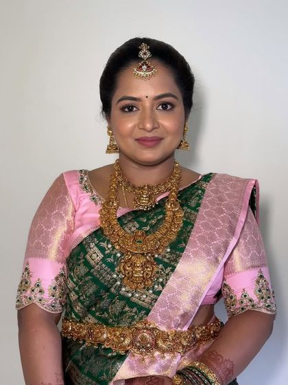 A timeless South Indian bridal guest look. The makeup features a warm, glowing base with soft smokey eyes to complement the client's green and pink silk saree and antique gold jewelry.
