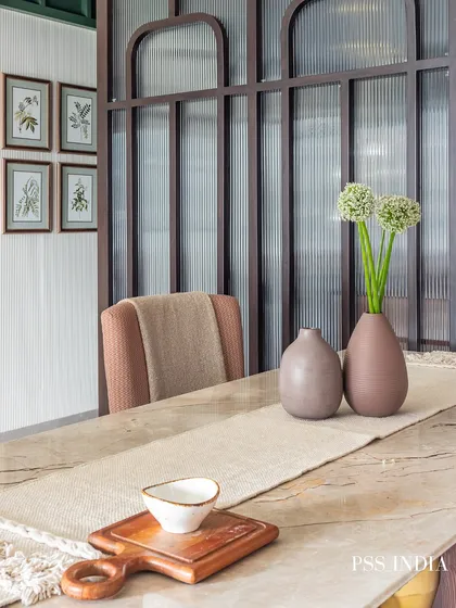 Another angle of the dining table with the fluted glass partition. The simple styling with muted vases and a natural runner allows the textures of the furniture and surrounding architecture to shine.
